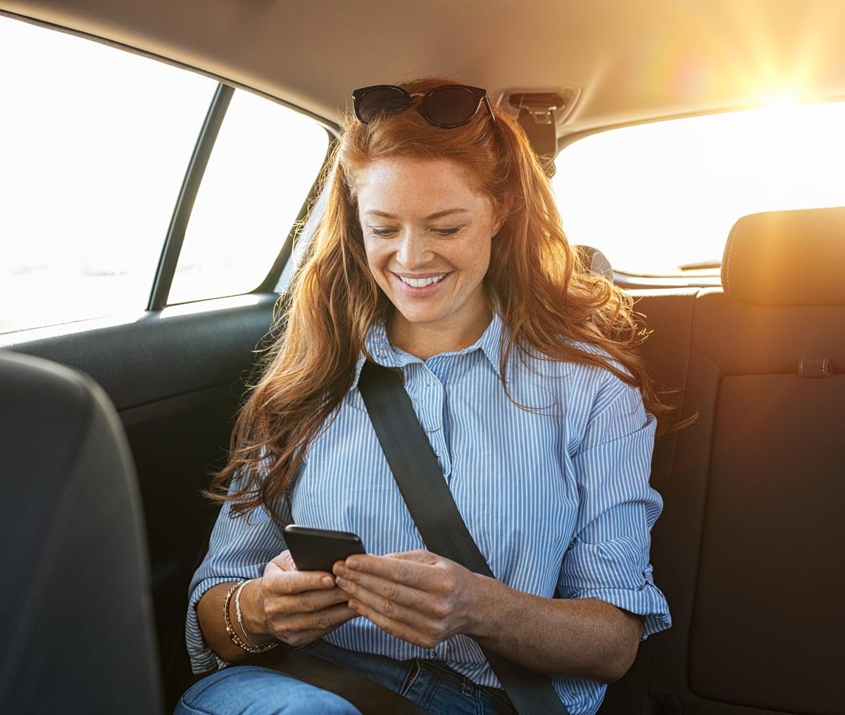 Femme regardant son téléphone assise à l'arrière d'une voiture